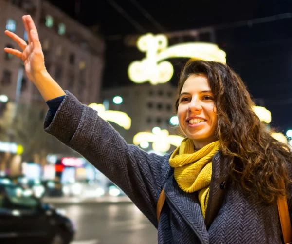 Girl calling taxi in urban environment at night